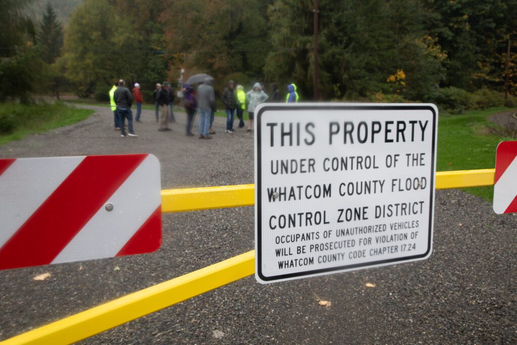 Whatcom County Public Works leads a group of locals, officials and politicians on a tour of an embankment built in Acme as a sign warns visitors of unauthorized entry.