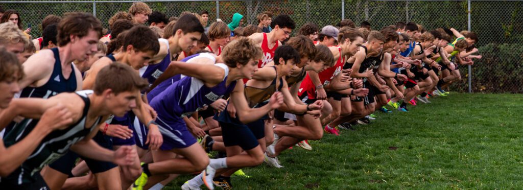 The boys varsity cross country participants take off in a row next to one another.