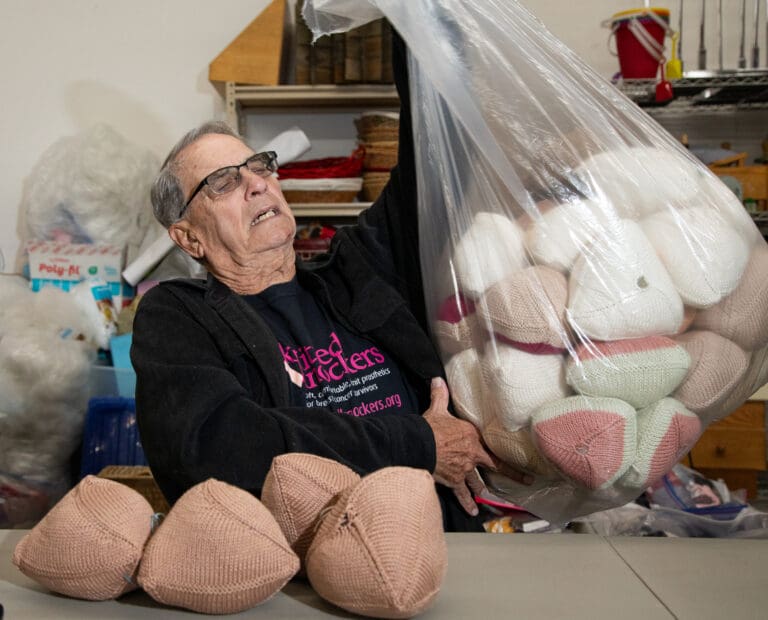 Ken "Knocker Dude" Malseed hauls a bag full of knitted knockers onto the table in the back storage area of Apple Yarns on Wednesday