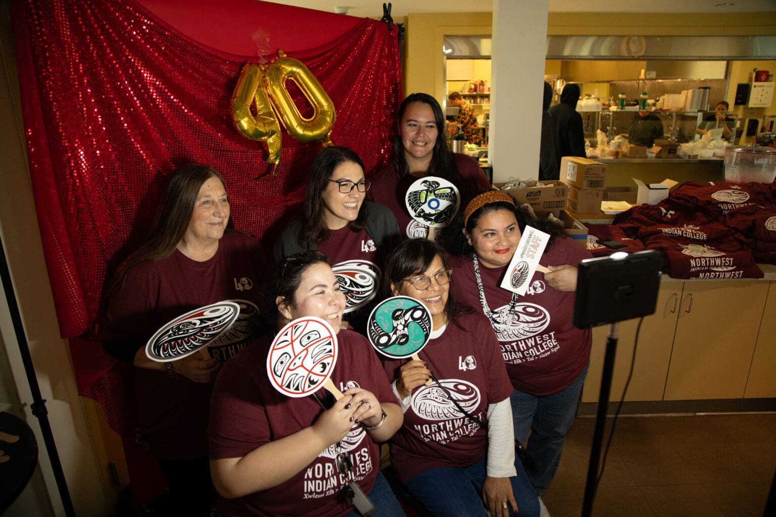 Organizers and volunteers at the Northwest Indian College's 40th anniversary pose for a group photo using the provided props.
