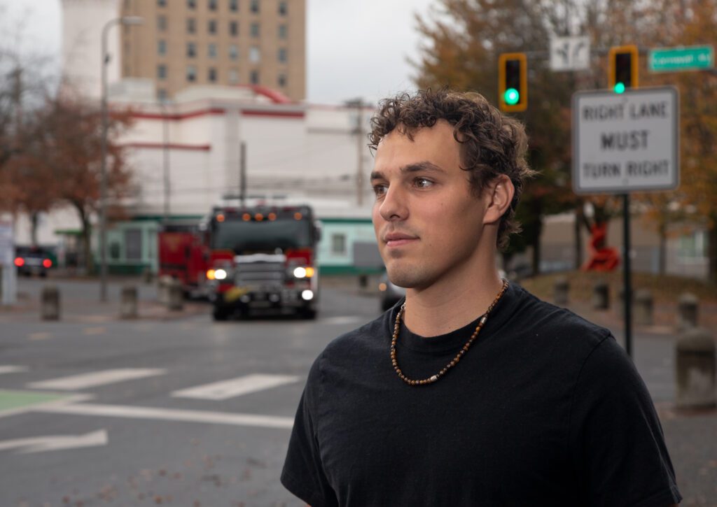 Brendan Mudd stands in downtown Bellingham as a firetruck pulls into the street behind him.