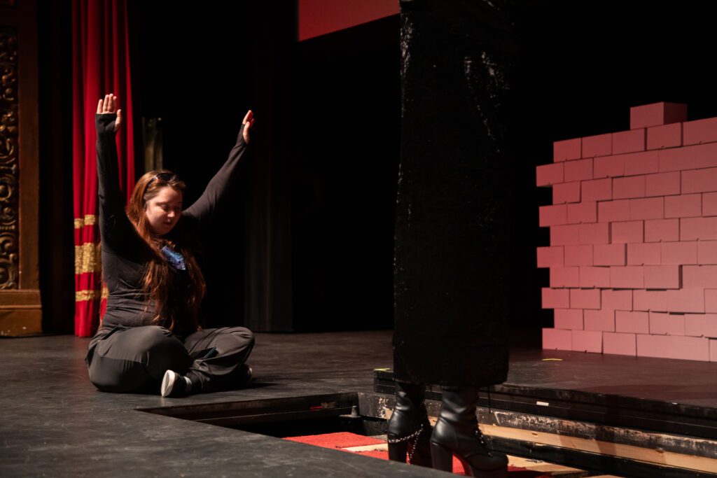 Director Megan Sutton lifts her hands in celebration as the stage lift successfully raises Heather Duncan as Frank-N-Furter up from under the stage.
