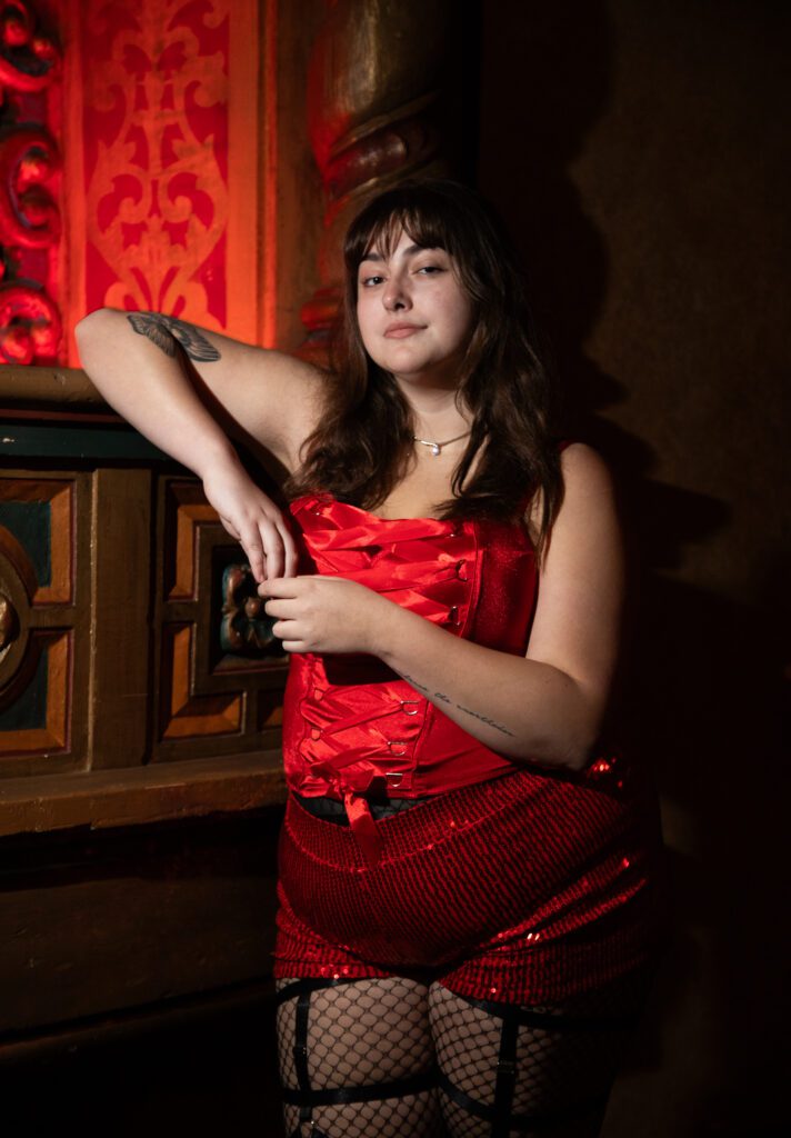 Taylor Daniels, 20, is performing as Lips and a Transylvanian in the show poses against the stage while wearing a bright red attire.