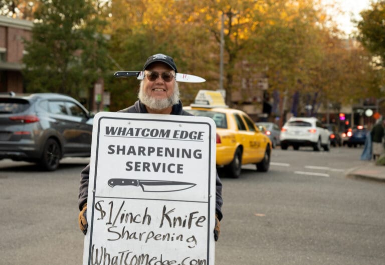 Truk Tolstad of Whatcom Edge holds his sign on the corner of State and Holly streets in downtown Bellingham on Tuesday