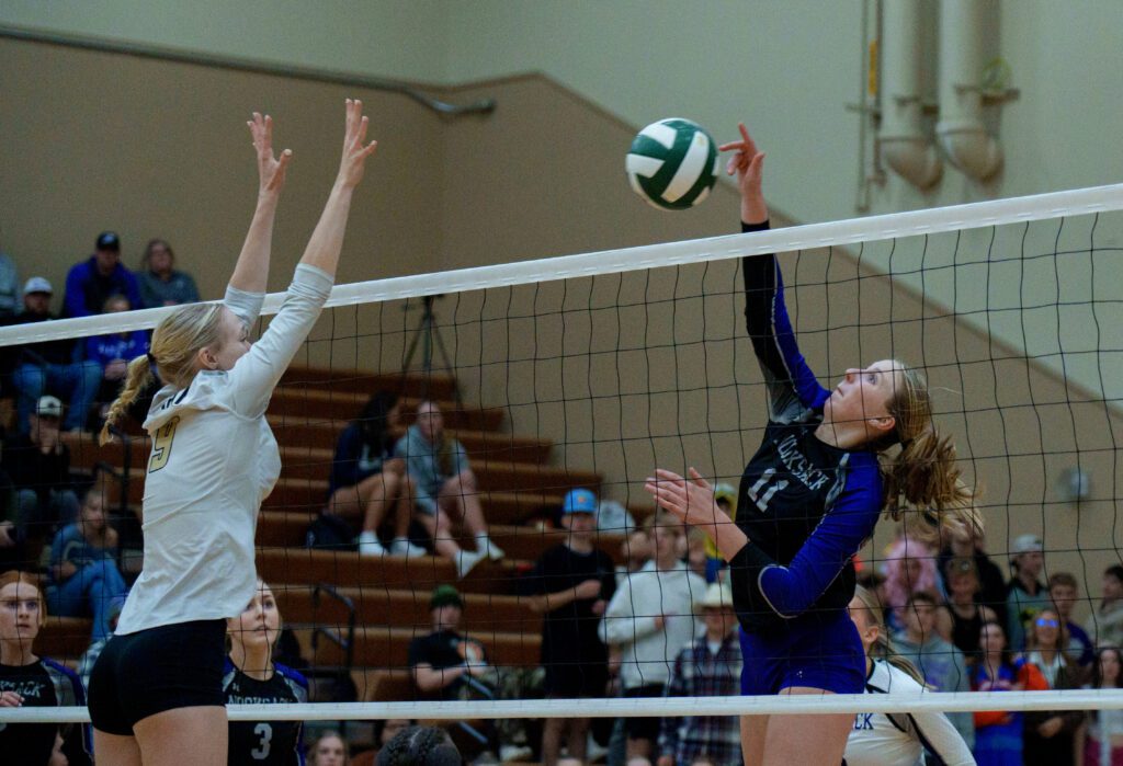 Nooksack Valley's Tana Hoekema spikes the ball over the net as a defender leaps up to block the shot.