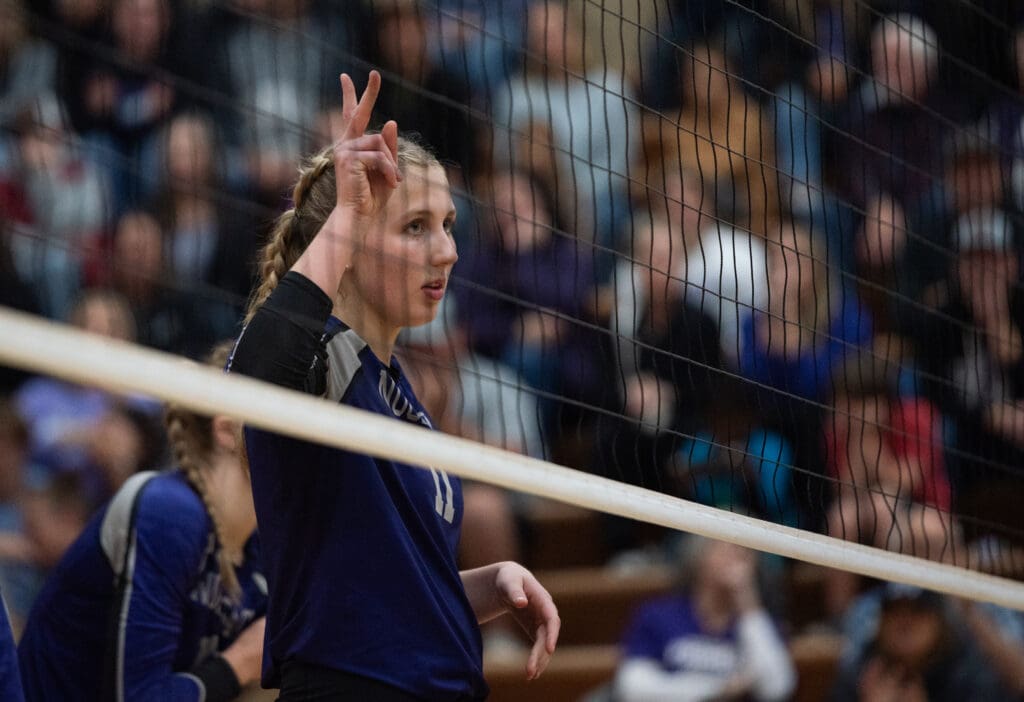 Nooksack Valley senior middle blocker Tana Hoekema holds up her fingers as a signal behind the volleyball net.