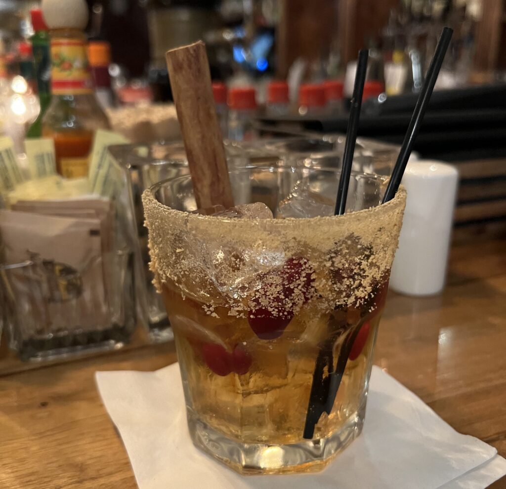 The Toasted Pecan Old Fashioned has a heavy helping of sugar on the rim and is served with two black straws and plenty of cranberriers.