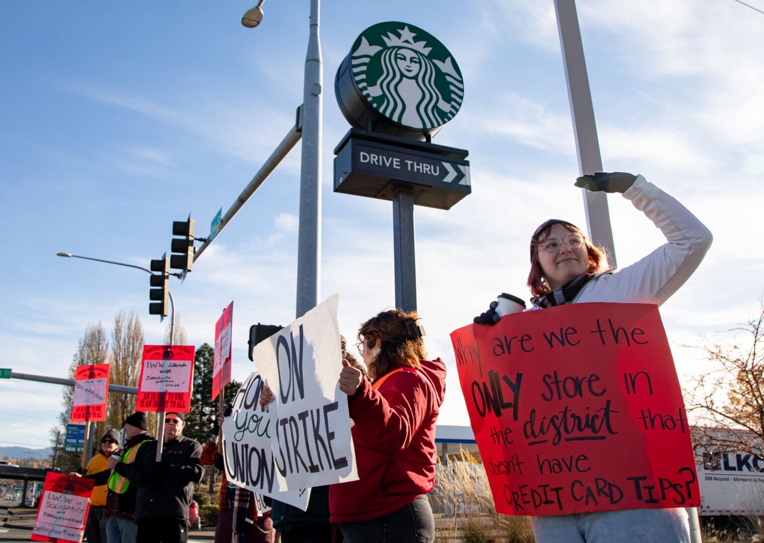 Supervisor Kelly Cabage, right, and other workers and supporters strike outside the Starbucks with bright red and white signs as they chant for rights.