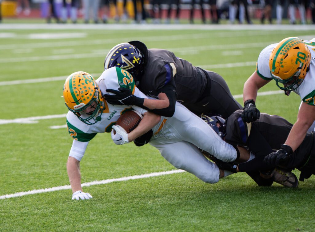 Lynden sophomore running back Maximus Assink is taken down by two North Kitsap defenders as a teammate fall in an attempt to tackle a defender.