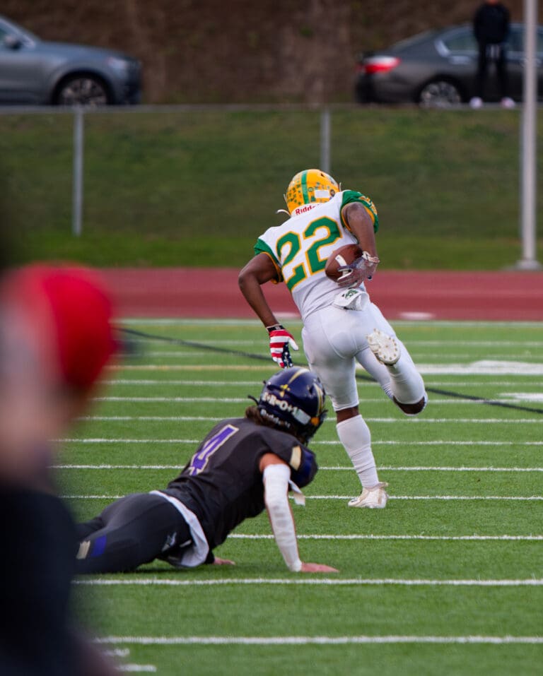 Lynden sophomore wide receiver Dani Bowler secures the ball behind his back as another player looks up from the ground.