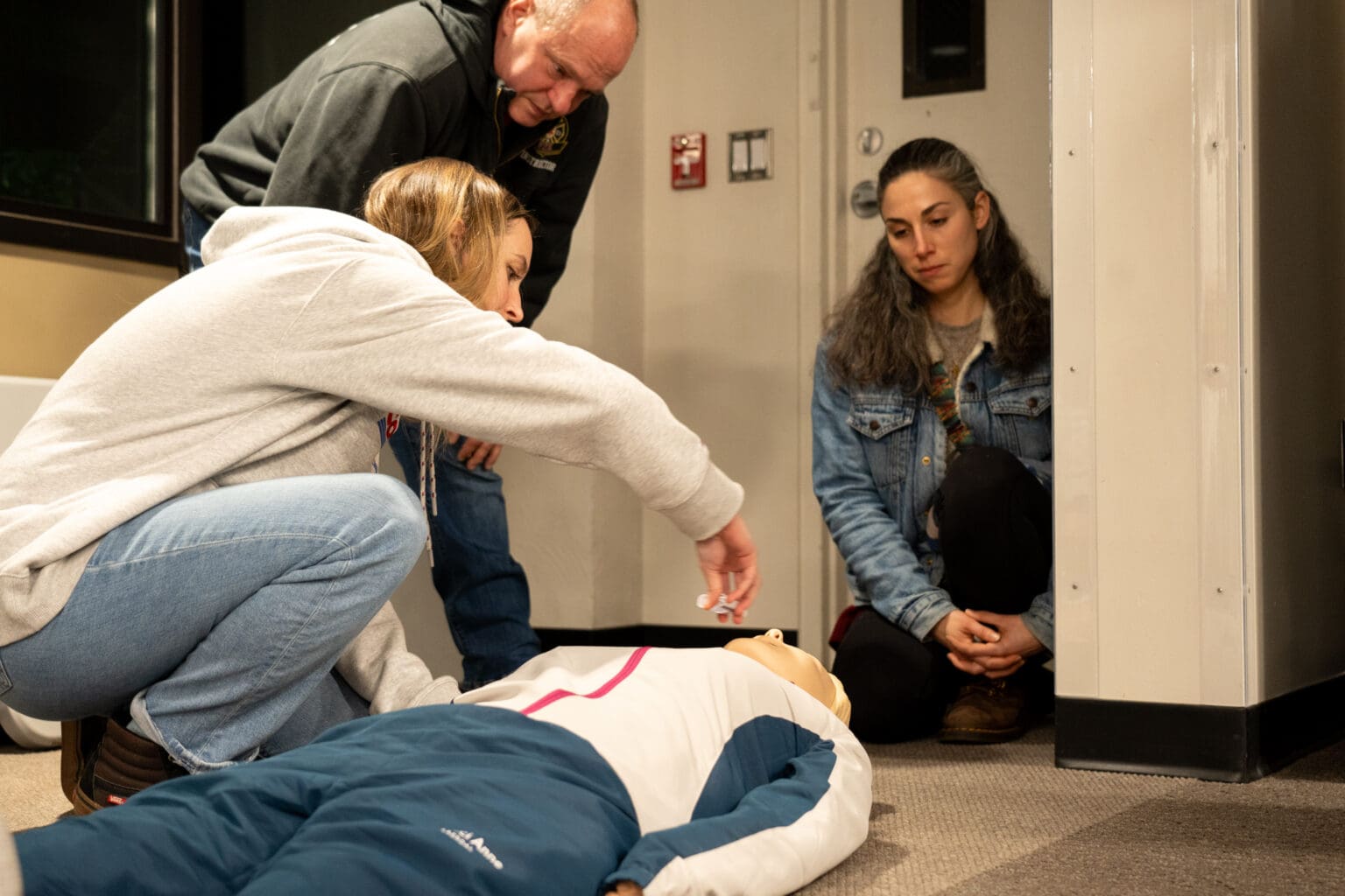 Bailey Rahn rehearses administering naloxone to a dummy in front of the instructor and another attendee.