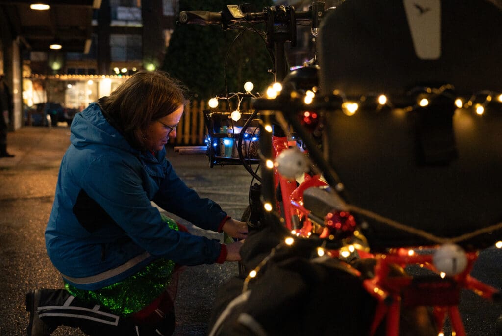 Mary Anderson a senior transportation planner at Whatcom Transit Authority (WTA) adjusting the decorations on her bike's wheel.