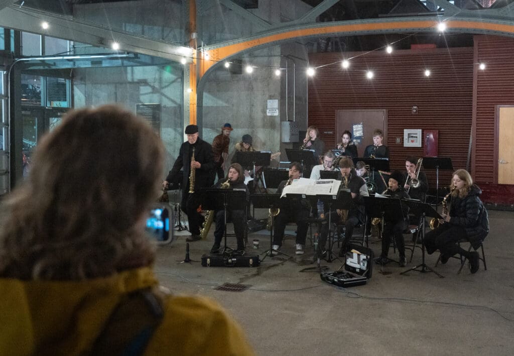 The Bellingham Youth Jazz Band sitting in rows with their bass instruments plays jazzy renditions of Christmas songs in the Depot Market Square pavilion.