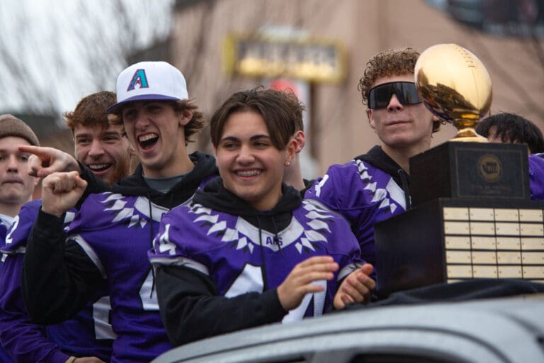 Anacortes football players cheer as they drive down Commercial Avenue with their 2A State Championship trophy.