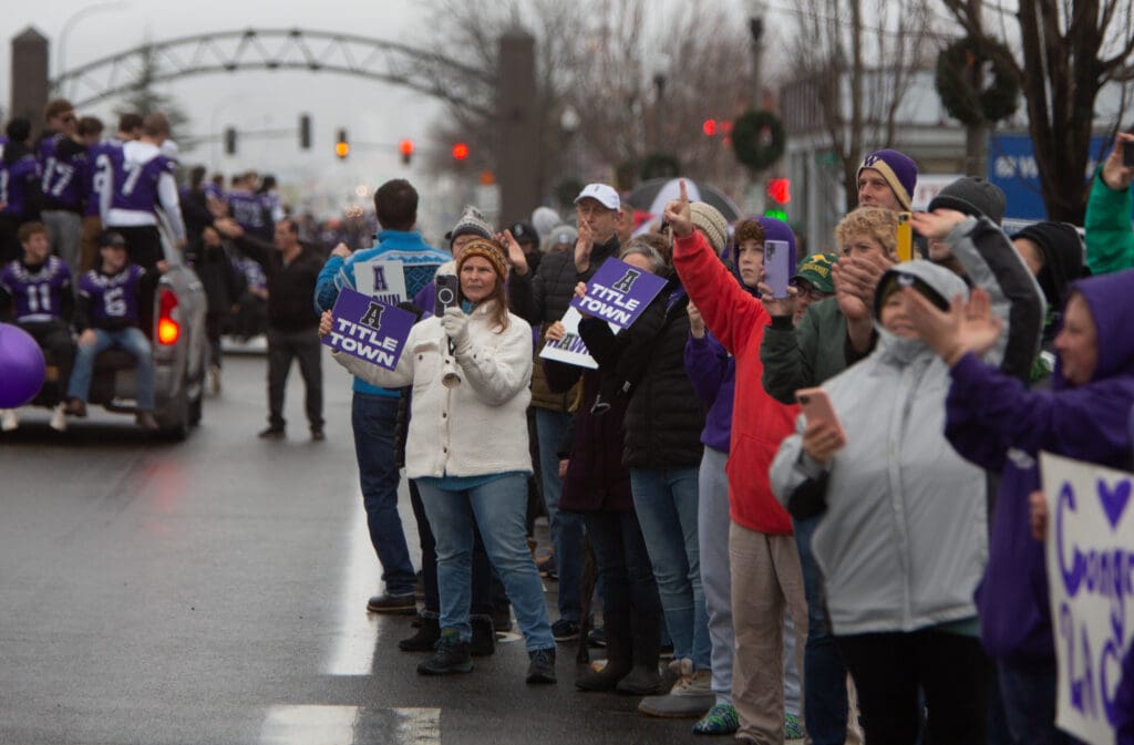 Supporters cheer, wave their signature purple signs and take photos of the football team as they parade down Commercial Avenue.