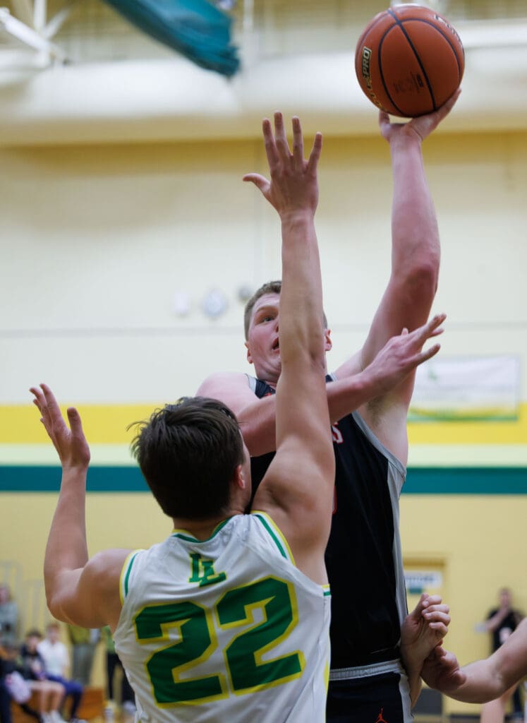 Bellingham’s Jesse Harward shoots a basket over Lynden’s Brant Heppner who is leaping to try and block the shot.