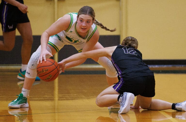 Lynden freshman Finley Parcher steals the ball from a Lake Stevens player who is kneeling on the ground.
