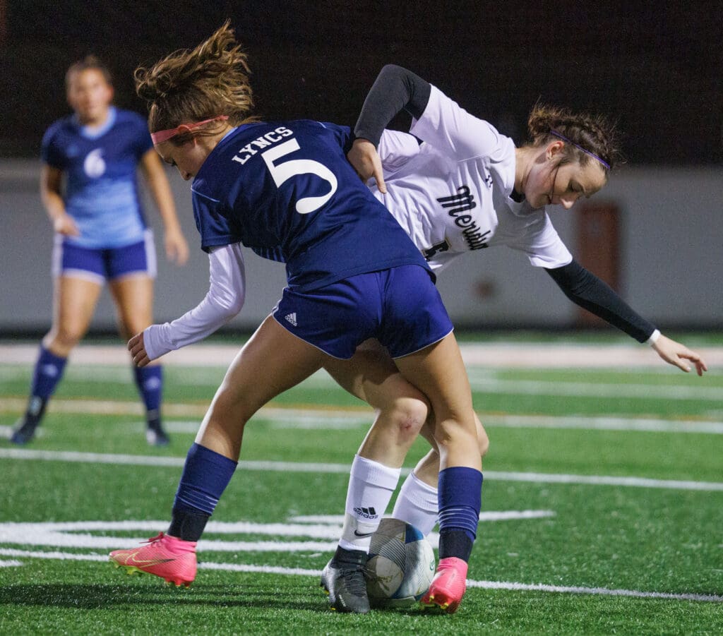 Nayla Speer and Meridian’s Erica Stotts battle for control of the ball as their legs get entangled.