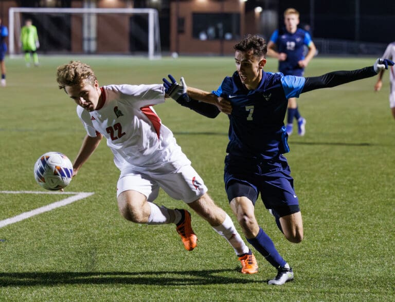 Western Washington University's Albin Jonsson battles for the ball against a Saint Martin’s University defender as they shove each away from each other.