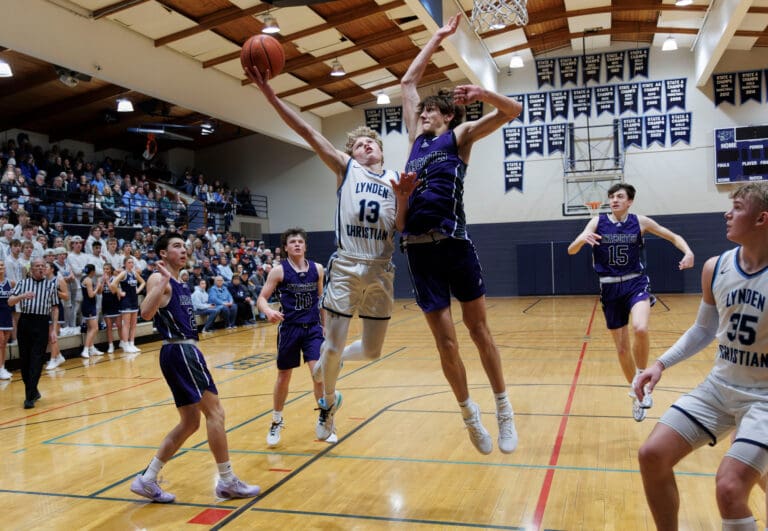 Anacortes’ Davis Fogle reaches for the swat against Lynden Christian’s Gannon Dykstra as they both leap above other players.