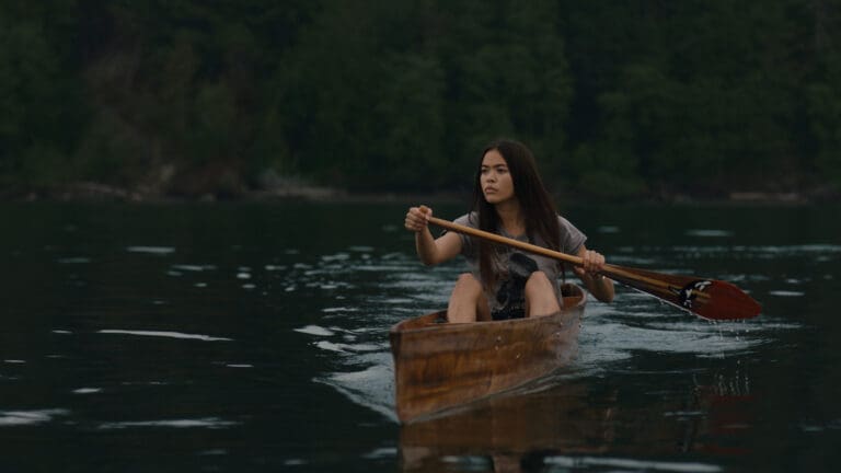 Ta’Kaiya Blaney as Tiss in "The Sound". She's rowing in a wooden canoe.
