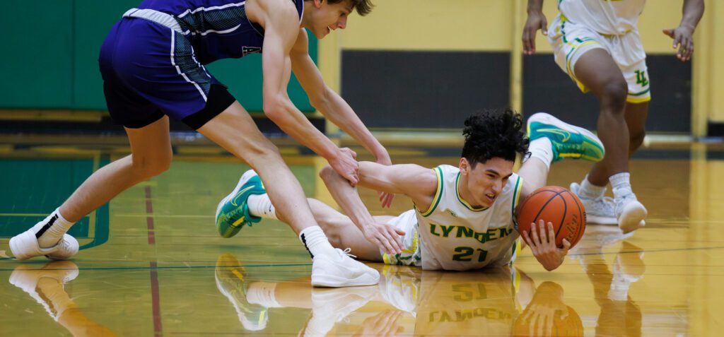 Lynden’s Anthony Canales grabs a loose ball as Anacortes’ Davis Fogle grabs his arm.