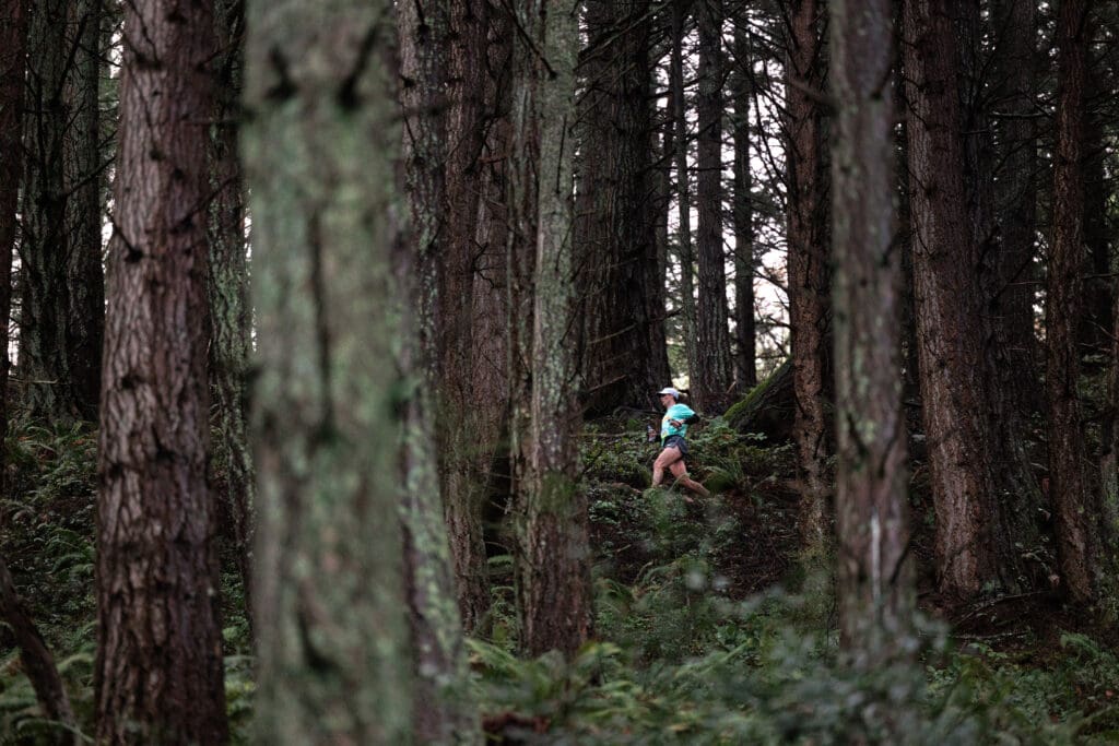 A runner competes in a trail race in the middle of the dense forest.