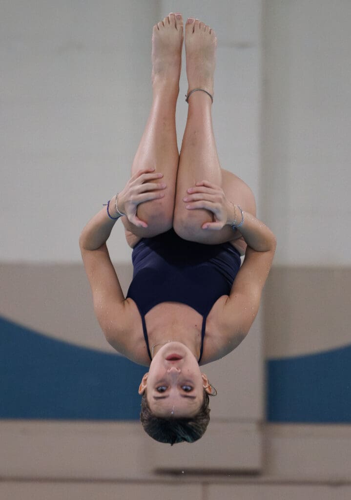 Squalicum’s Kenna Andersen performs a back tuck dive as she's momentarily upside down midair while holding her knees.