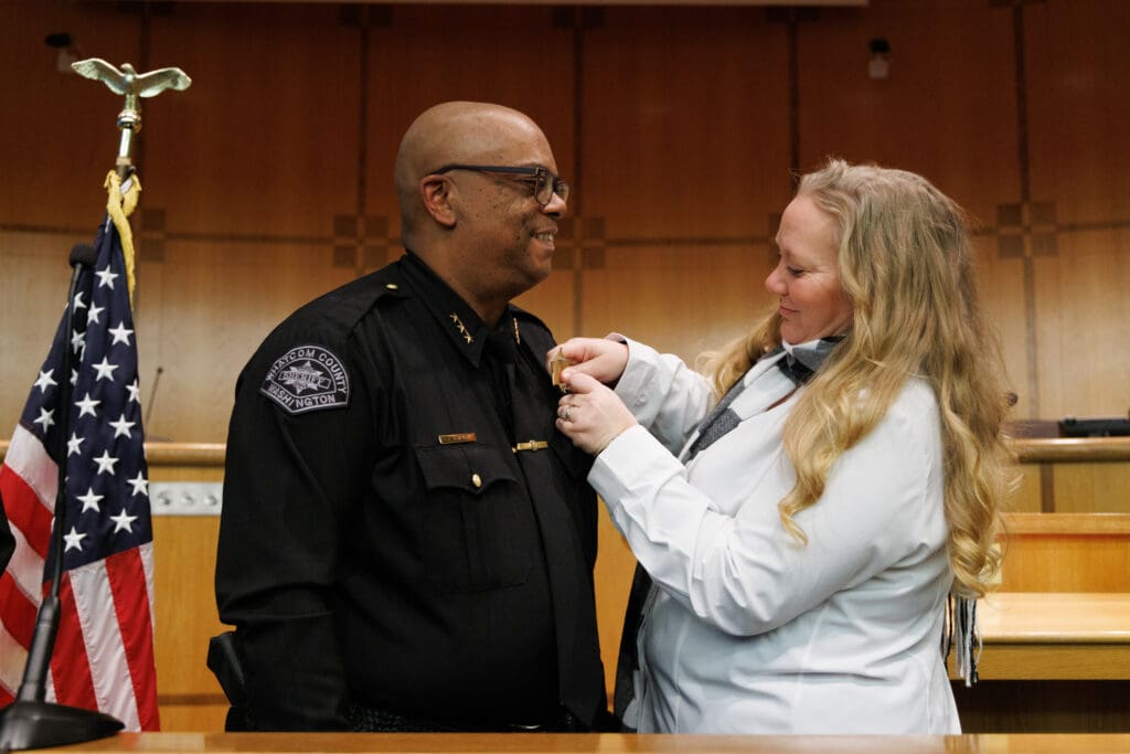 Whatcom County Sheriff Donnell Tanksley has his new badge put on by his wife, Jessie, after his swearing-in.