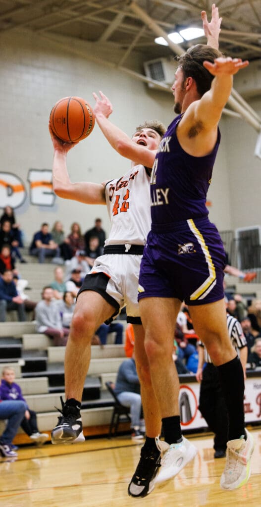 Blaine’s Noah Tavis takes a shot as Nooksack Valley's Joseph Brown tries for the block from the side as spectators watch from the bleachers.