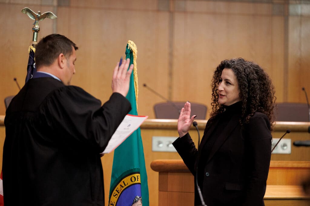 Judge Jonathan Rands to incoming Whatcom County Assessor Rebecca Xczar at the Oath of Office Ceremony held in the County Council Chambers at the Whatcom County Courthouse next to the Washington State flag.