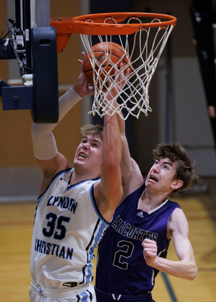 Lynden Christian’s Jeremiah Wright goes up for a shot as an Anacortes defender tries to block by reaching for the ball as they leap up together.