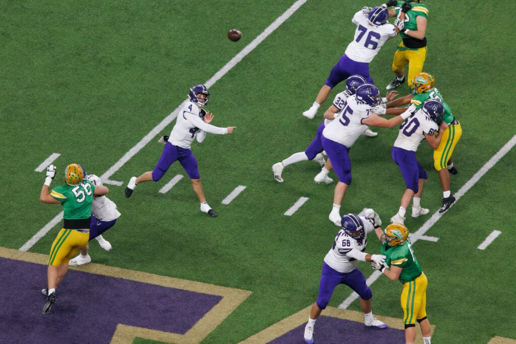Anacortes quarterback Rex Larson throws the ball as his teammates block other players from reaching him.