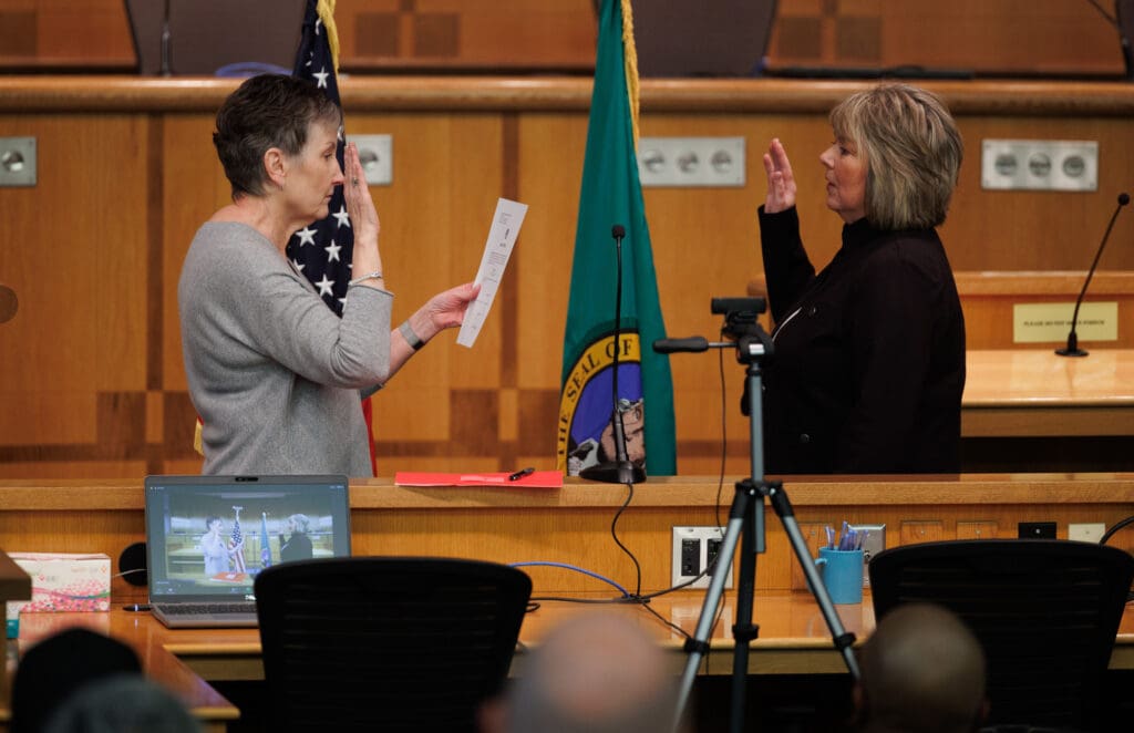 Outgoing Whatcom County auditor Diana Bradrick, left, swears in new auditor Stacy Henthorn during the Oath of Office Ceremony held in the County Council Chambers while they are being recorded by a laptop next ot Diana Bradrick.