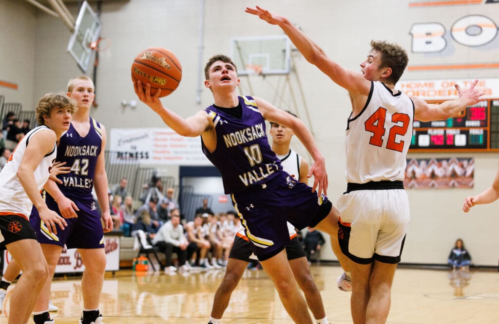 Nooksack Valley's Caden Heutink tries for the shot as he falls out of bounds while driving to the hoop while other players look to block the shot.