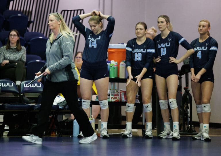 Western head coach Diane Flick-Wiliams reacts with her team after losing the second set as her coach walks off with a clipboard.