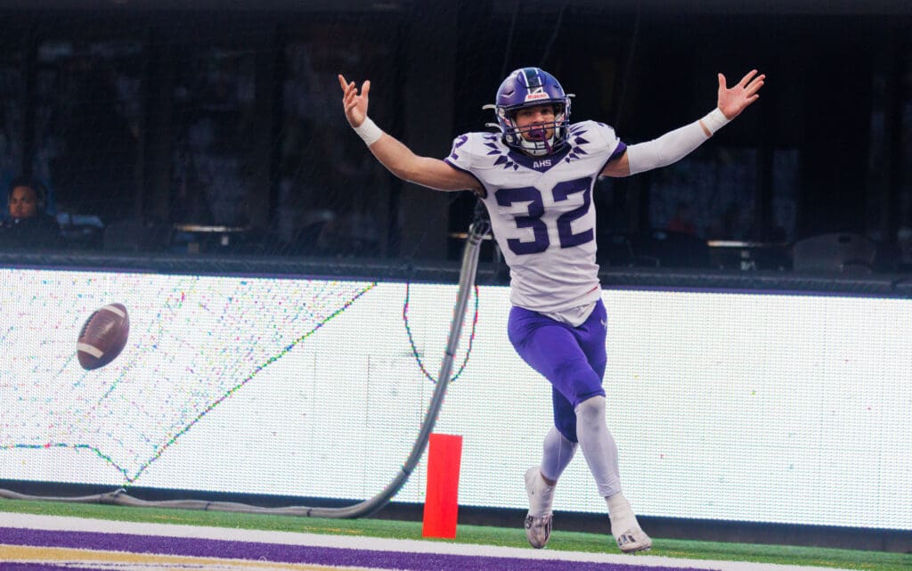 Anacortes running back Brock Beaner celebrates his touchdown off a blocked punt with his arms raised in the air.