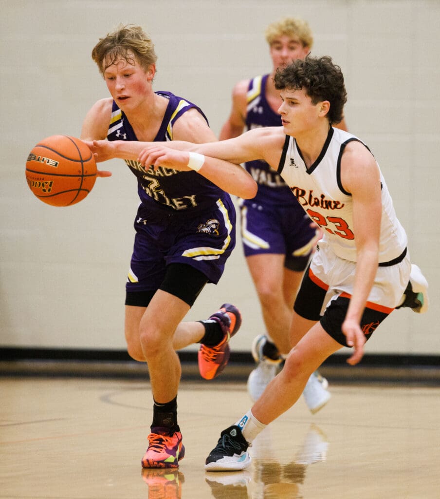 Nooksack Valley's Cole Coppinger makes the steal as Blaine’s Jesse Deming tries to grab the loose ball while another player rushes from behind them.
