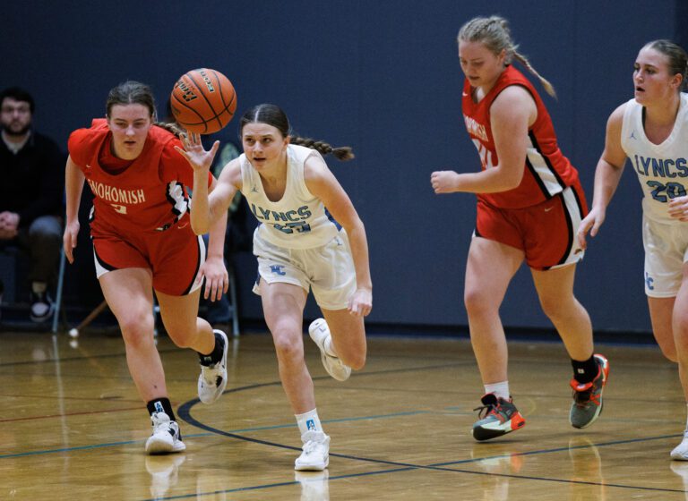Ellie Pierce tries for a fast break bucket surrounded by the opposing team and her teammate as the basket ball is within her grasp.