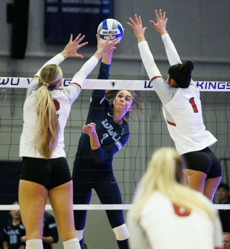 Western's Delaney Speer tries to put a spike between two Central Washington blockers who are leaping to try and block.
