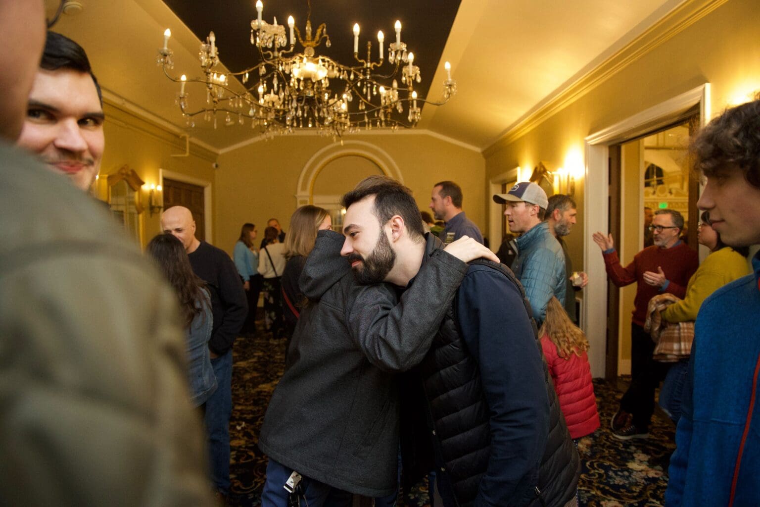 Bellingham City Council at-large candidate Jace Cotton hugs Joel Pitts-Jordan in the middle of a crowded room.