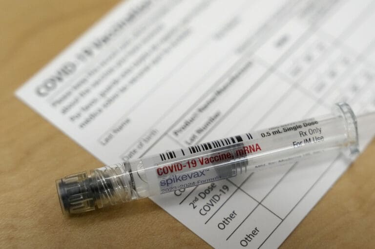 A COVID vaccine tube lies on a vaccine card.
