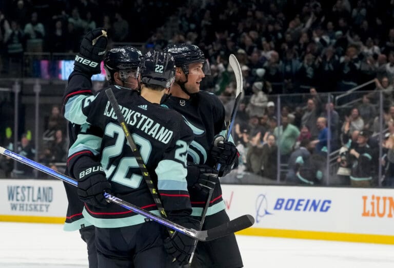 Seattle Kraken defenseman Brian Dumoulin, right, celebrates with his teammates as they hug and look to the spectators.