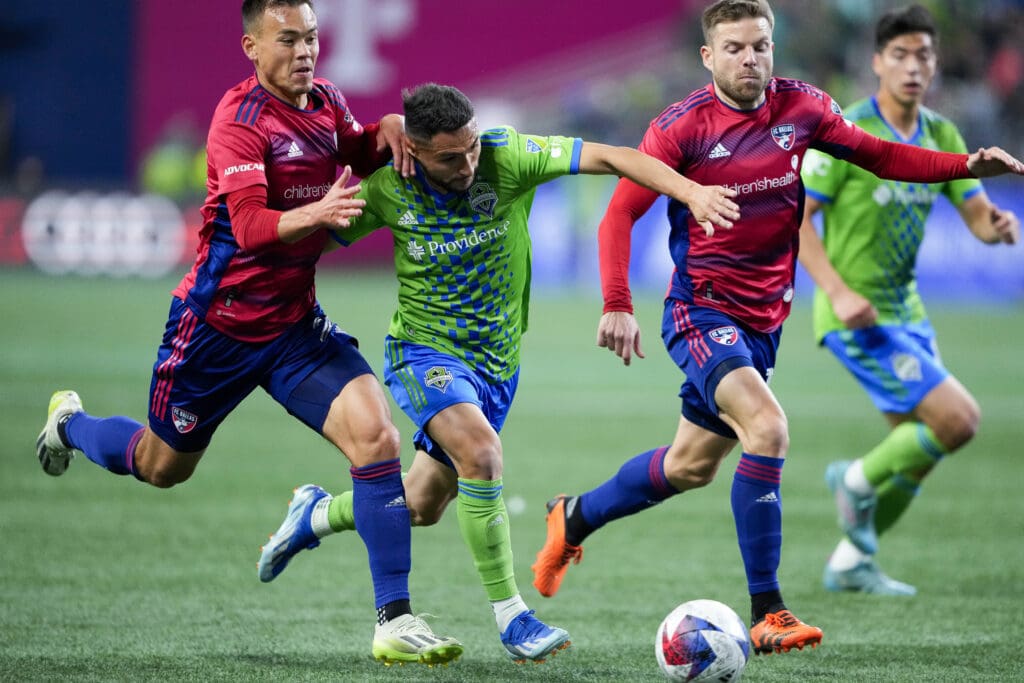 Seattle Sounders midfielder Cristian Roldan, second from left, drives the ball in between two FC Dallas defenders.