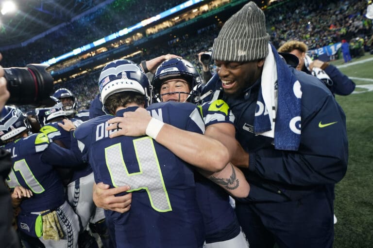 kicker Jason Myers (5) celebrates with punter Michael Dickson (4) as they hug each other in a crowded huddle.