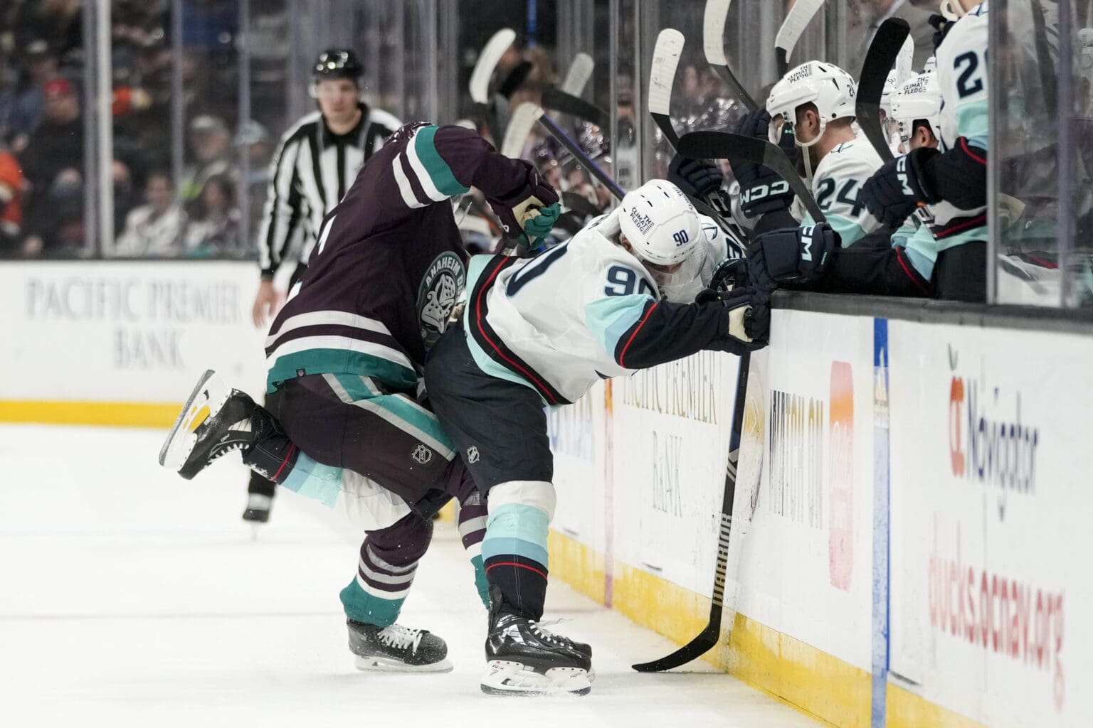 Seattle Kraken left wing Tomas Tatar (90) is shoved by Anaheim Ducks center Trevor Zegras (11) into the glass barrier separating the rink from the sidelines.