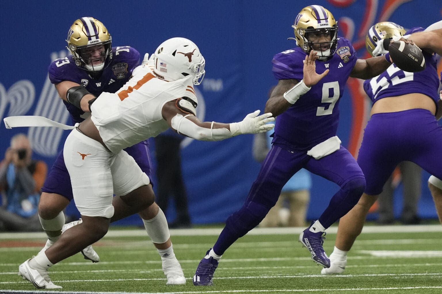 Washington quarterback Michael Penix Jr. (9) scrambles with the ball against Texas defensive end Justice Finkley (1) as the defender himself is being grabbed by Micheal Penix Jr's teammate.