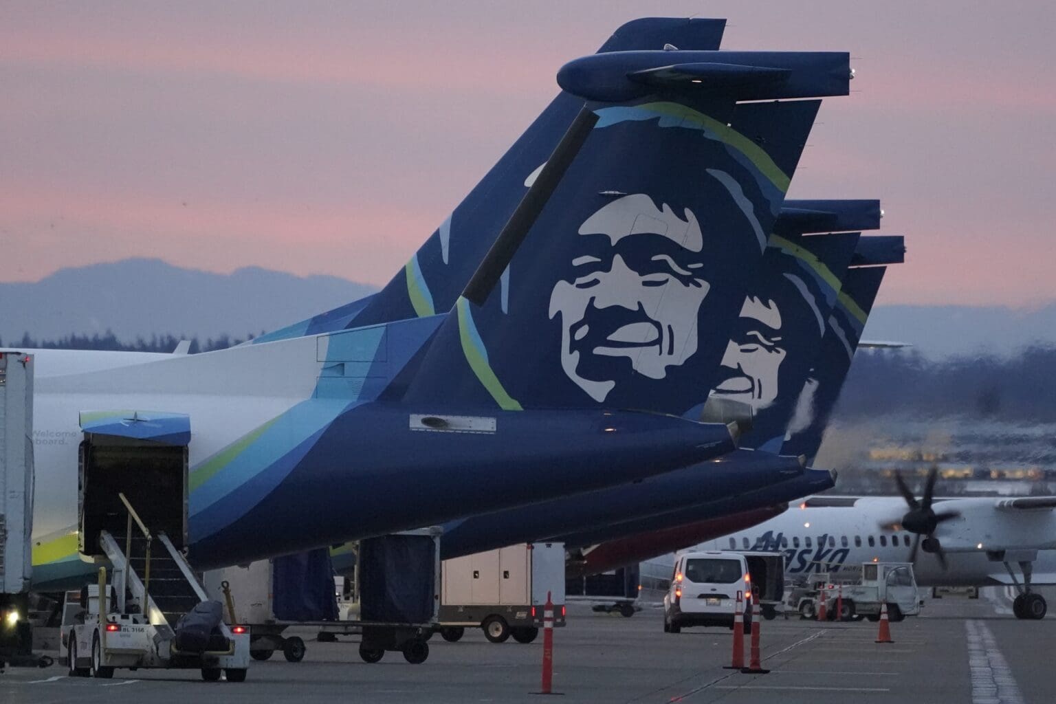 Alaska Airlines planes are shown parked at gates at sunrise