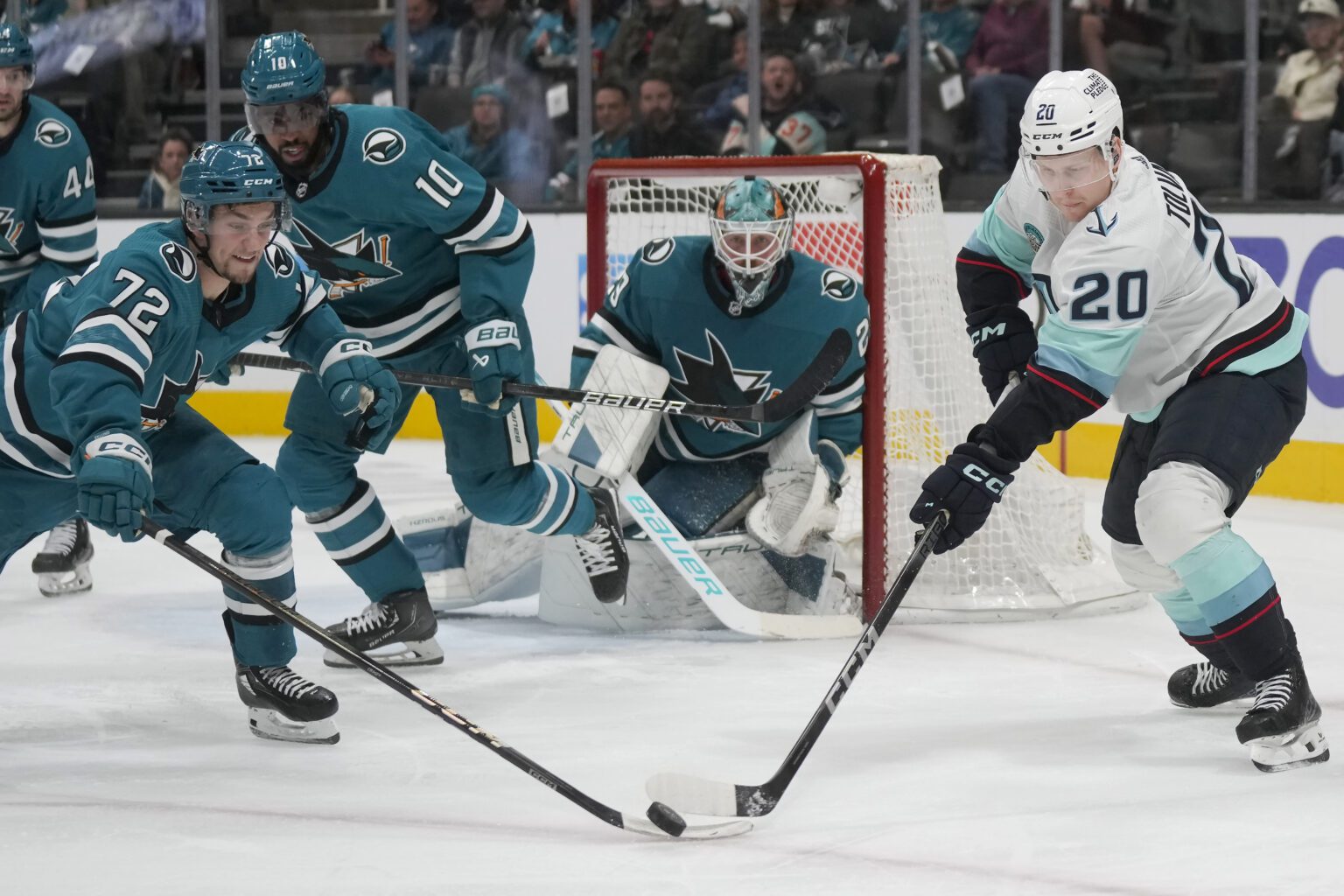 San Jose Sharks left wing William Eklund (72) reaches for the puck against Seattle Kraken right wing Eeli Tolvanen (20) with teammates behind them to help defend the goal.