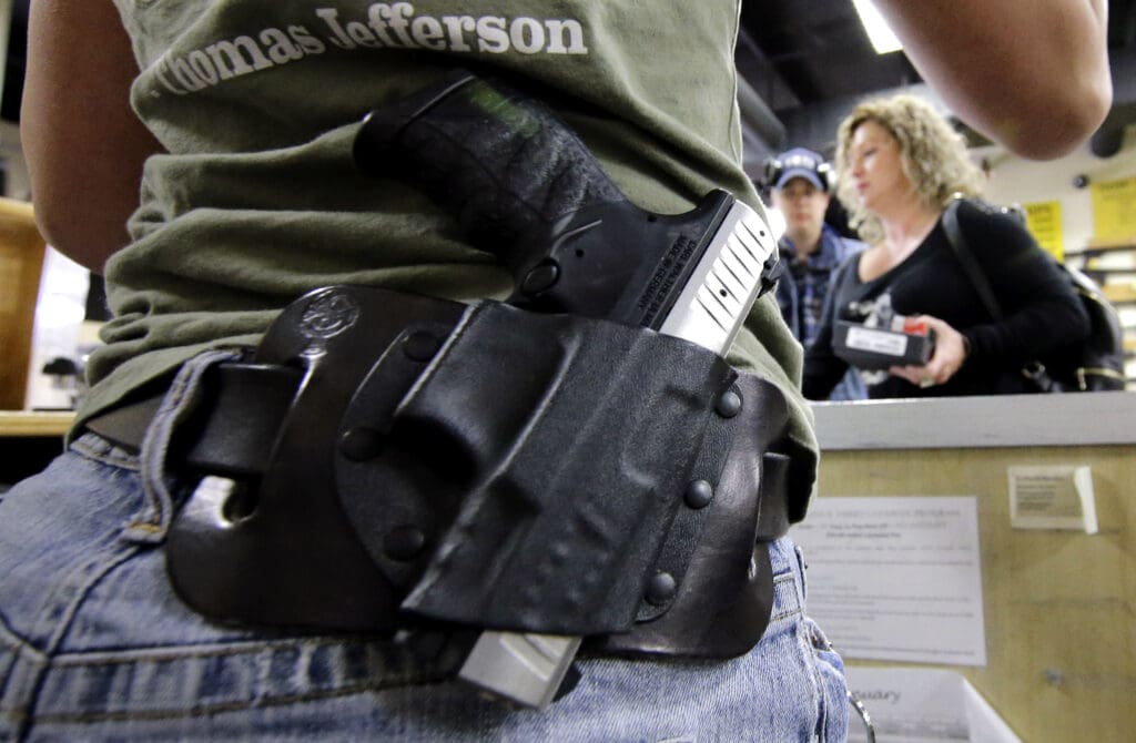 A photo of the side of a person's hip where they have a holstered gun on their belt.